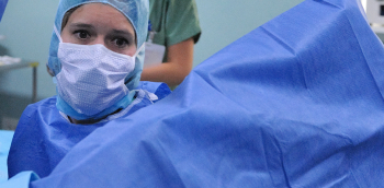 Un médecin avec un masque et en blouse bleu effectue un prélévement sur une personne