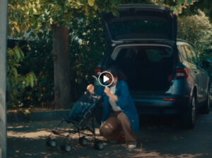 Une femme bataille à plier sa poussette. Capture d'écran de la vidéo campagne 'Parents' #FaitesDesParents