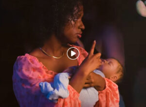 Une jeune femme est en soirée et elle tient un bébé dans ses bras.